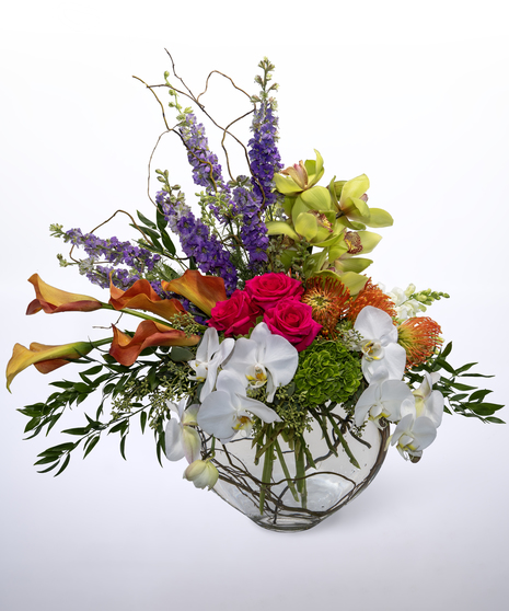 hydrangea, roses, protea, calla lilies, larkspur, snap dragon and cymbidium orchids in a glass vase