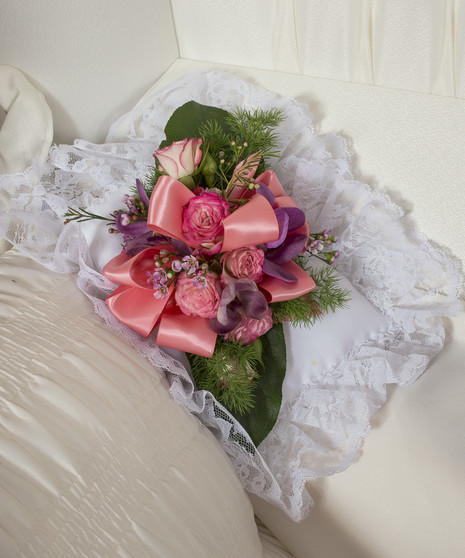 soft colored flowers atop a satin pillow for casket
