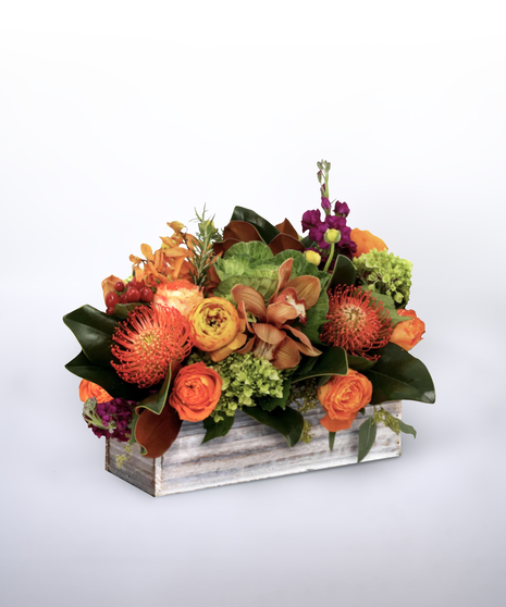 hydrangea, sunflowers, orange dahlias, orange calla lilies, orange and yellow roses and protea in a green pot